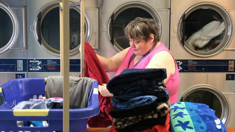 Customer Cheryl Minor folds her clothes during the LAUNDRY LOVE event. Photo by: Nancy Carlson