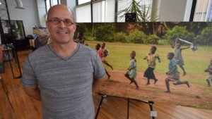 Michael Jensen is pictured by one of his large format photographs on display inside the Intersection Agency on Walnut Street during ArtsWalk 2017. Photo by: Mike Rhodes