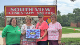 Muncie Public Library (MPL) content management coordinator Katherine Mitchell, Muncie Community Schools certified teacher librarians Rhonda Cowan and Melinda Sheffield, and MPL assistant director Beth Kroehler show off the UCAT Read! Card outside of South View Elementary School. Photo by: Akilah S. Nosakhere