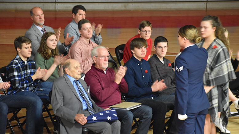 U.S. Marine and World War II veteran Junior Howell is presented a flag of honor by WHS graduate and active duty Sr. Airman Katie Leach. They are surrounded by members of the WHS AP U.S. History class who organized the Veterans Day program. Photo by: Maelyn Hobbs