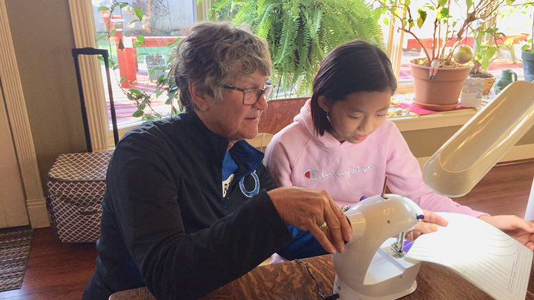 Nancy passes some sewing skills on to Jing Jing. Photo by: John Carlson