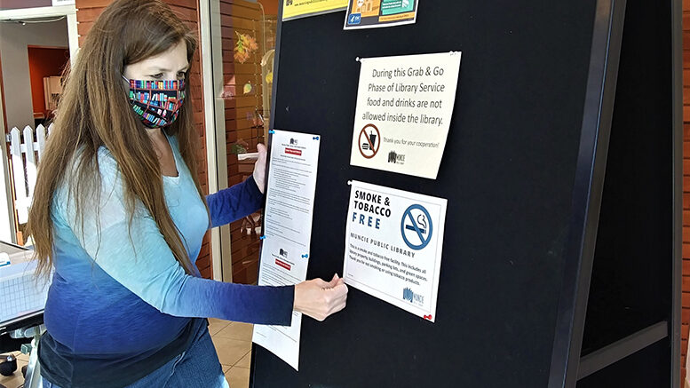 MPL facilities staff post signs for the new Smoke & Tobacco Free Policy. Photo by Susan Fisher