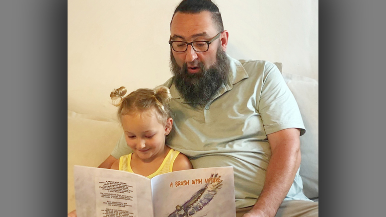 A father and daughter reading one of the first copies of “A Brush with Nature.” Photo by Red-tail Land Conservancy.