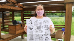 Shanna Hurd, Youth Services Supervisor at Maring-Hunt Library, displays a coloring poster for kids at a recent outdoor event. Photo by Susan Fisher