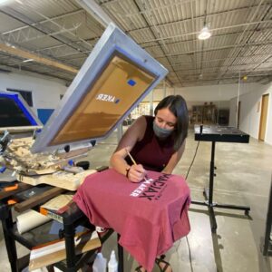 A participant in the Maker Mondays screen printing workshop is adding final touches to her t-shirt design. Photo by: Kyra Zylstra