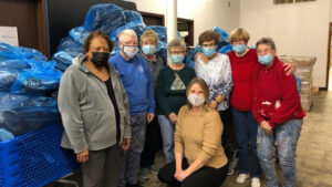 Members of Muncie Altrusa Club are pictured with bags of backpacks filled with healthy snacks and a book for distribution to East Washington Academy and Northview Schools prior to the holiday break. Photo provided.