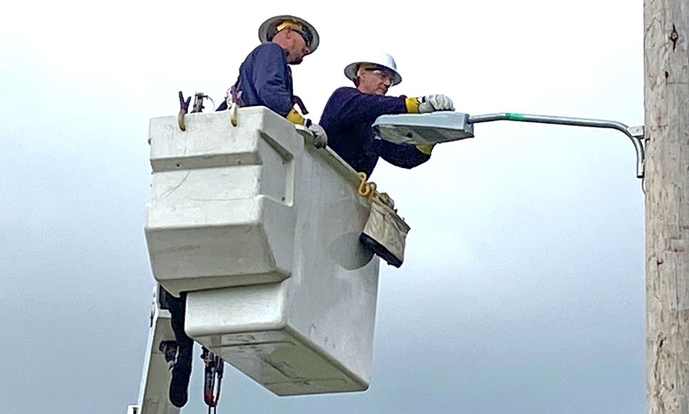 Muncie Mayor Dan Ridenour is pictured in the bucket truck during a mock demonstration of the streetlight conversion. WLBC's Steve Lindell is seen below, videotaping the mayor. Photo provided by Indiana & Michigan Power