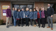 The seven honorees are pictured wearing their gray jackets along with Home Instead staff and leadership team members.
