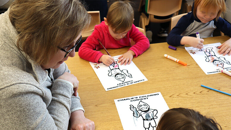 Suzie Jones, project coordinator in the Office of Community Engagement at Ball State, visits with the kiddos at United Day Care as they color their pages for Charlie’s Coloring Challenge.