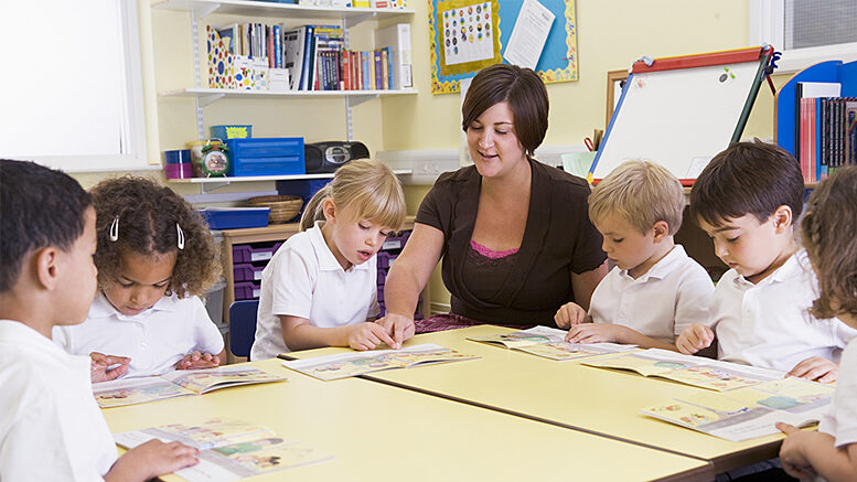 A teacher works with students during a reading lesson. Photo by storyblocks