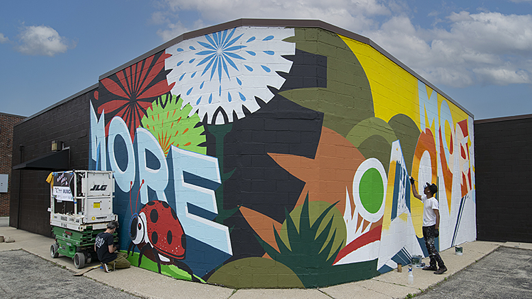 Volunteers continue work on the 'More Love' mural on south Walnut street. Photo by Mike Rhodes