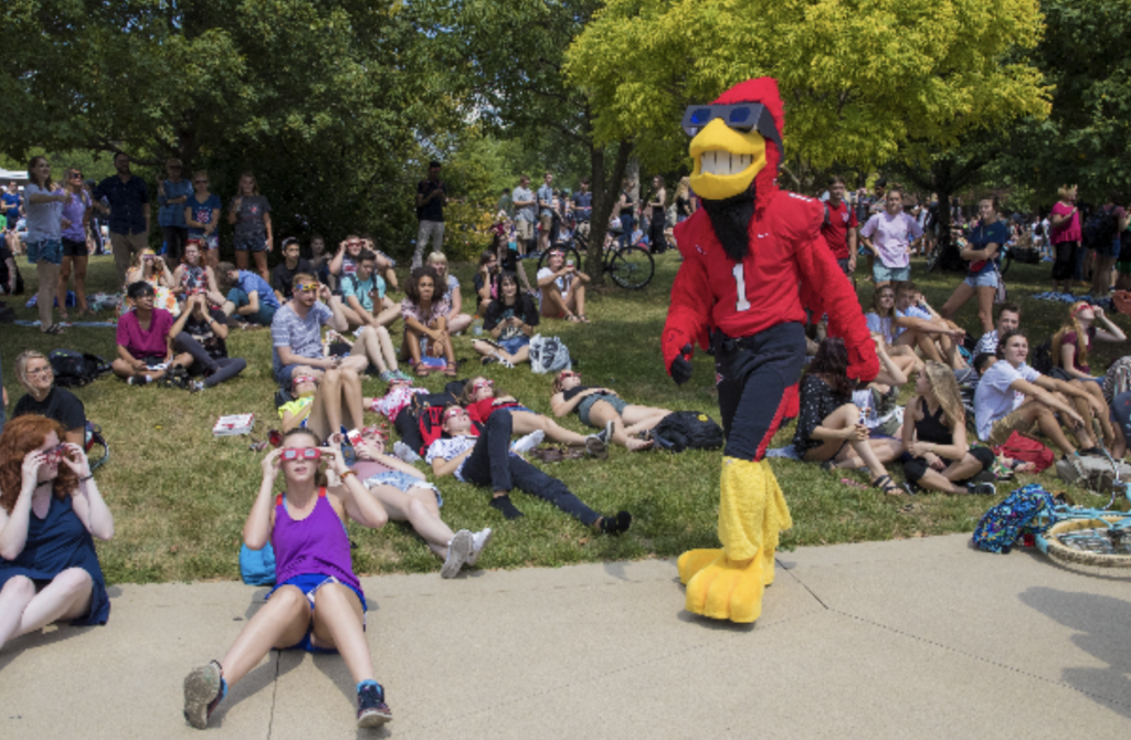 Ball State students, community guests, and Charlie Cardinal wear their eclipse glasses for the 2017 partial eclipse viewing party. The community will experience a similar environment on campus at the October 14, 2023 partial eclipse party. Photo by Ball State University