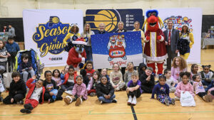 Children gather with Pacers Sports & Entertainment staff, Indiana Pacers mascot Boomer, Indiana Fever mascot Freddy Fever, Indiana Pacemates, Muncie Mayor Dan Ridenour and Muncie Police Department Deputy Chief Melissa Criswell for the Big Toy Giveaway at Muncie Central High School on Tuesday, Dec. 9, 2025.