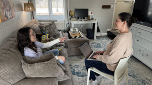 Muncie Scholar House Director, Ashley Soldaat (right), converses with a Muncie Scholar in her student apartment, while her young son reads a book. Photo provided.