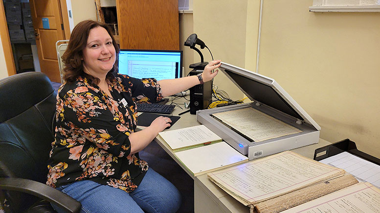 Sara McKinley, Carnegie Library Manager & MPL Archivist, demonstrates the current method of digitalizing historic documents. McKinley will purchase upgraded equipment using the recent Carnegie Corporation grant. Photo by Kailey Armstrong, PR Volunteer Muncie Public Library.